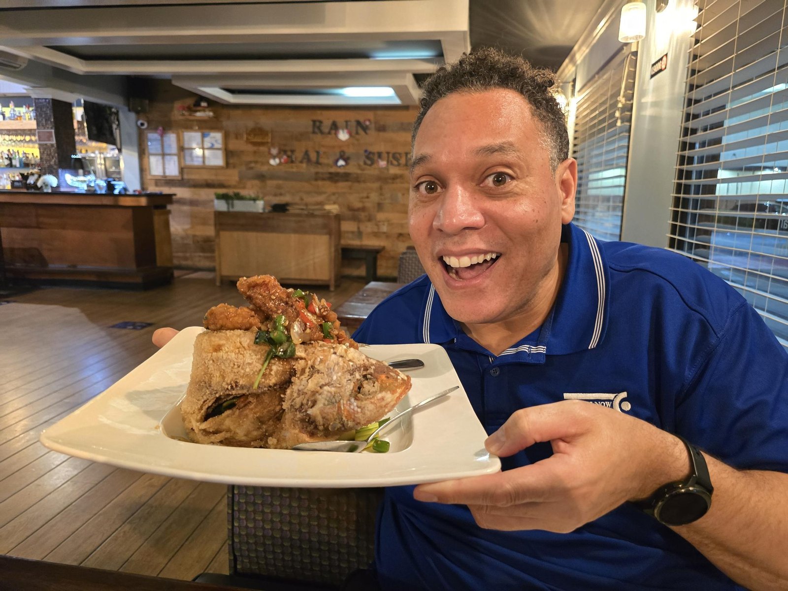 Nick holding a plated fish dish at Rain Thai & Sushi